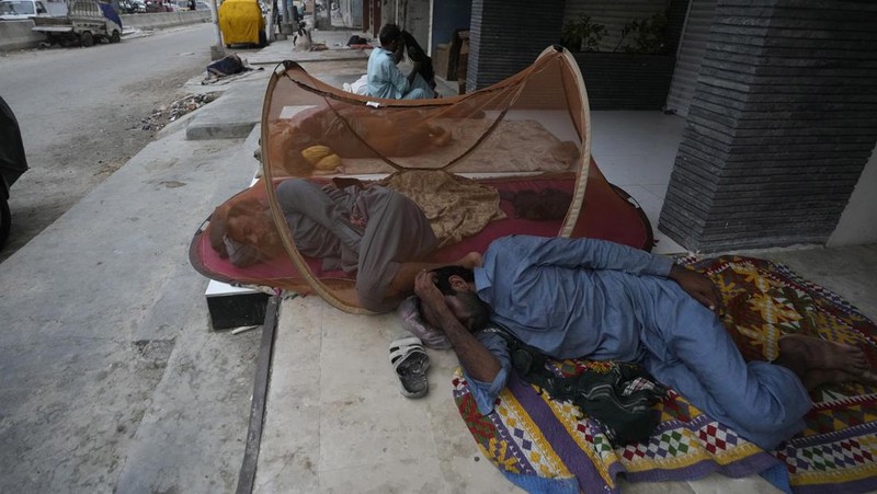 Para buruh tidur di pinggir jalan pada pagi hari musim panas yang terik di Karachi, Pakistan, Rabu (29/5/2024). (AP Photo/Fareed Khan)