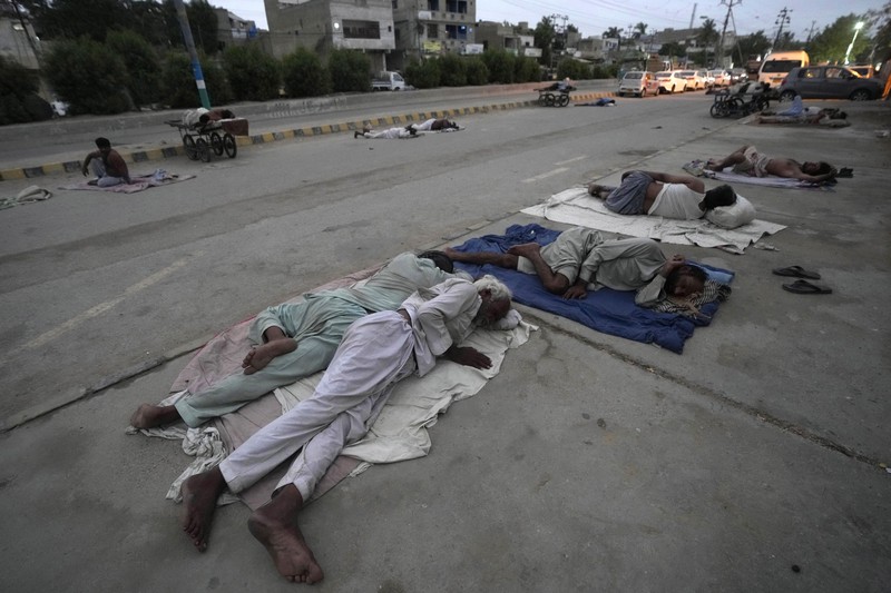 Para buruh tidur di pinggir jalan pada pagi hari musim panas yang terik di Karachi, Pakistan, Rabu (29/5/2024). (AP Photo/Fareed Khan)