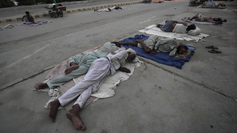 Para buruh tidur di pinggir jalan pada pagi hari musim panas yang terik di Karachi, Pakistan, Rabu (29/5/2024). (AP Photo/Fareed Khan)