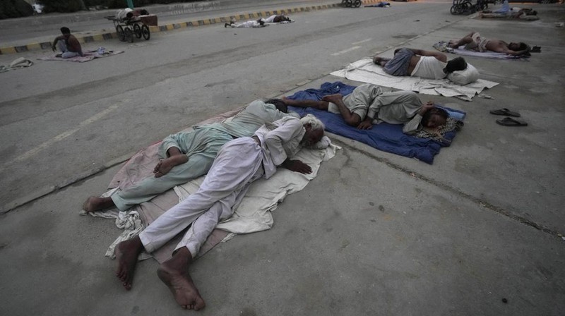 Para buruh tidur di pinggir jalan pada pagi hari musim panas yang terik di Karachi, Pakistan, Rabu (29/5/2024). (AP Photo/Fareed Khan)