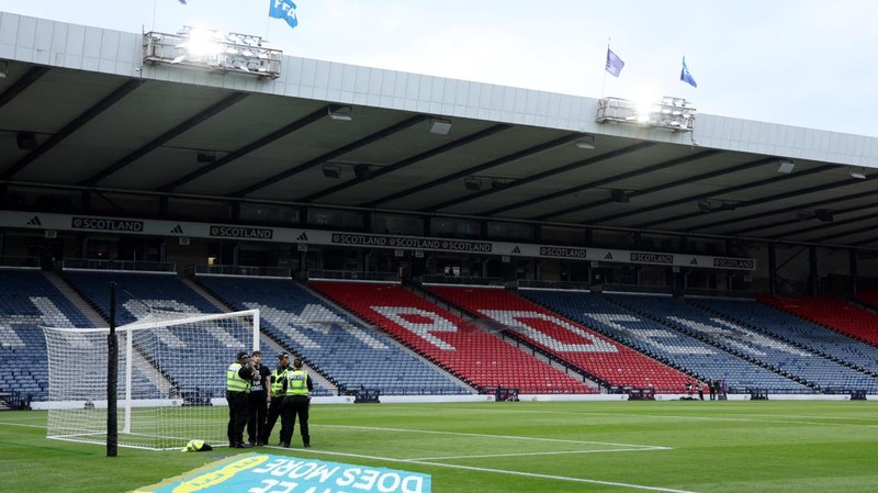 Polisi menahan seorang pengunjuk rasa yang diikat ke tiang gawang di Hampden Park, Glasgow, Skotlandia, Jumat (31/5/2024). (REUTERS/Russell Cheyne)