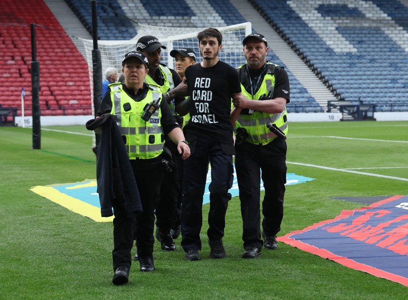 Polisi menahan seorang pengunjuk rasa yang diikat ke tiang gawang di Hampden Park, Glasgow, Skotlandia, Jumat (31/5/2024). (REUTERS/Russell Cheyne) Polisi menahan seorang pengunjuk rasa yang diikat ke tiang gawang di Hampden Park, Glasgow, Skotlandia, Jumat (31/5/2024). (REUTERS/Russell Cheyne)