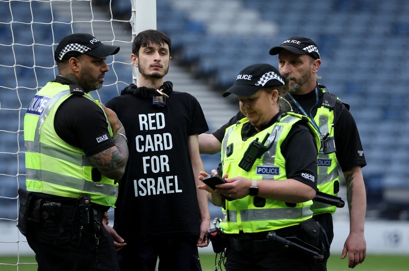 Polisi menahan seorang pengunjuk rasa yang diikat ke tiang gawang di Hampden Park, Glasgow, Skotlandia, Jumat (31/5/2024). (REUTERS/Russell Cheyne) Polisi menahan seorang pengunjuk rasa yang diikat ke tiang gawang di Hampden Park, Glasgow, Skotlandia, Jumat (31/5/2024). (REUTERS/Russell Cheyne)