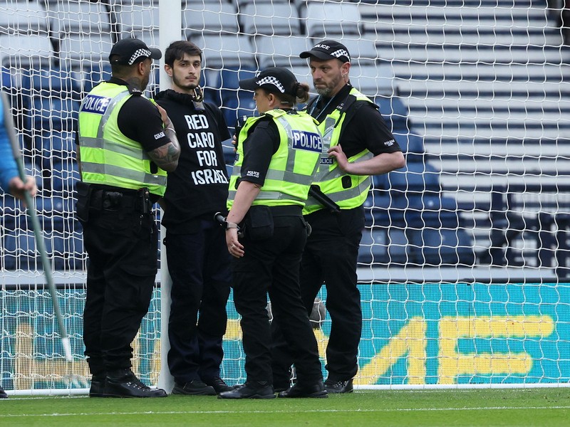 Polisi menahan seorang pengunjuk rasa yang diikat ke tiang gawang di Hampden Park, Glasgow, Skotlandia, Jumat (31/5/2024). (REUTERS/Russell Cheyne) Polisi menahan seorang pengunjuk rasa yang diikat ke tiang gawang di Hampden Park, Glasgow, Skotlandia, Jumat (31/5/2024). (REUTERS/Russell Cheyne)