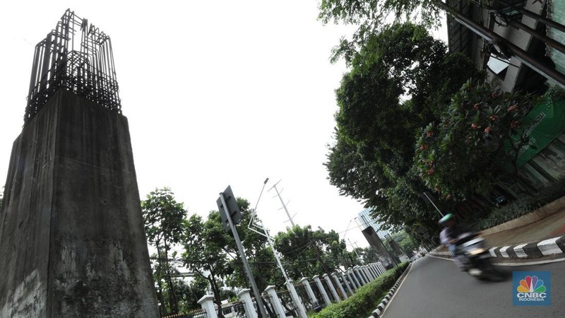 Sejumlah kendaraan melintas di antara tiang monorel yang terhenti pembangunannya di Jalan Rasuna Said, Jakarta, Senin (3/6/2024). (CNBC Indonesia/Tri Susilo)