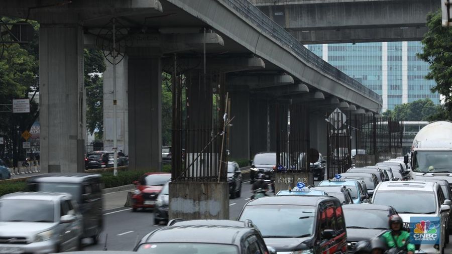 Sejumlah kendaraan melintas di antara tiang monorel yang terhenti pembangunannya di Jalan Rasuna Said, Jakarta, Senin (3/6/2024). (CNBC Indonesia/Tri Susilo)