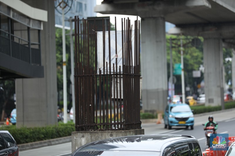 Sejumlah kendaraan melintas di antara tiang monorel yang terhenti pembangunannya di Jalan Rasuna Said, Jakarta, Senin (3/6/2024). (CNBC Indonesia/Tri Susilo)