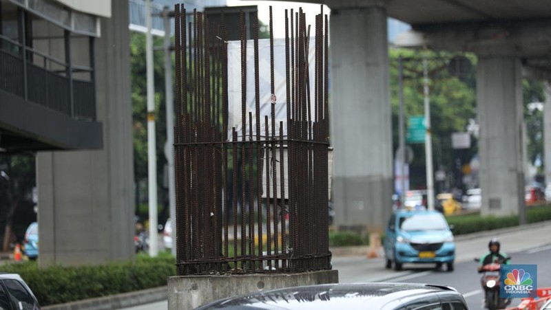 Sejumlah kendaraan melintas di antara tiang monorel yang terhenti pembangunannya di Jalan Rasuna Said, Jakarta, Senin (3/6/2024). (CNBC Indonesia/Tri Susilo)