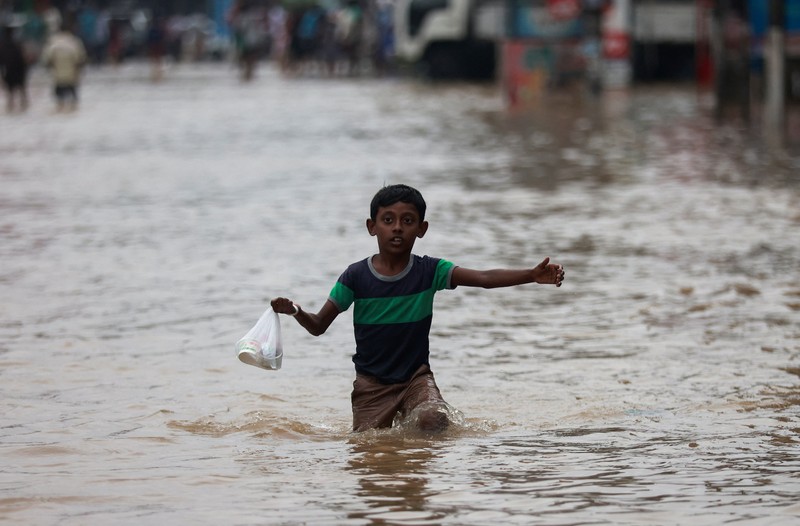 Penduduk desa berjalan melalui jalan yang banjir di Biyagama, Sri Lanka 2 Juni 2024. (REUTERS/Dinuka Liyanawatte)