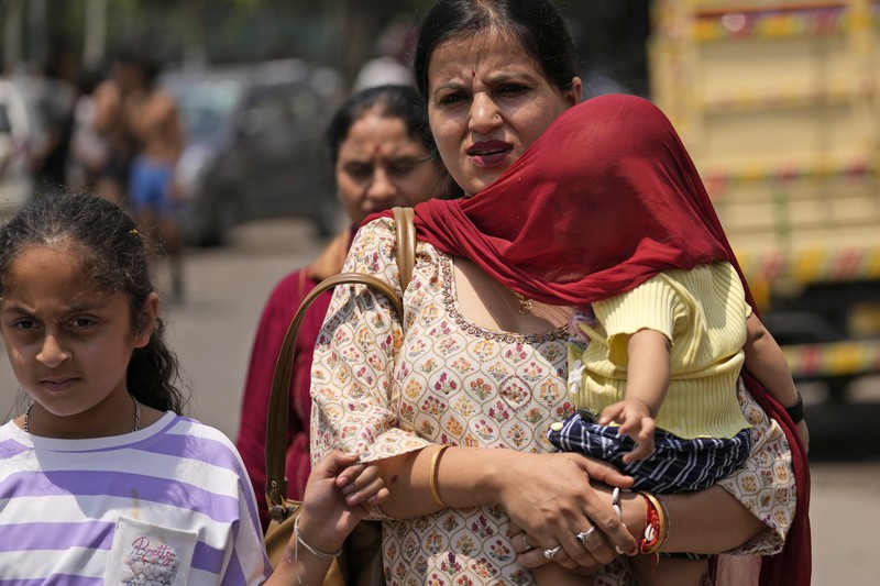 Seorang pria menggendong seorang anak dengan kepala ditutupi handuk untuk melindunginya dari panas di Jammu, India, Minggu, 2 Juni 2024. Seorang pria menggendong seorang anak dengan kepala ditutupi handuk untuk melindunginya dari panas di Jammu, India, Minggu, 2 Juni 2024. (AP Photo/Channi Anand)