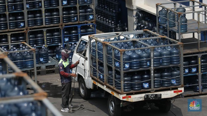 Pekerja memindahkan Galon air mineral dengan alat berat di distributor Aqua di kawasan Jakarta, Selasa (4/6/2024). (CNBC Indonesia/Tri Susilo)
