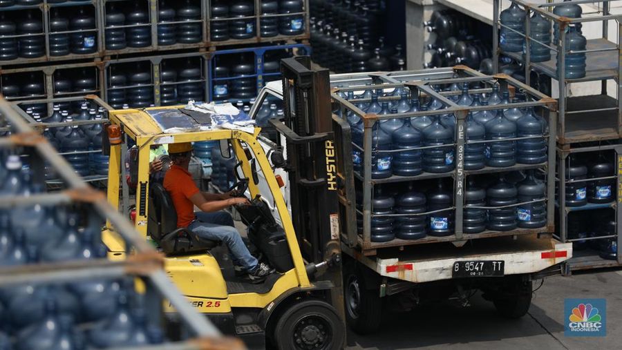 Pekerja memindahkan Galon air mineral dengan alat berat di distributor Aqua di kawasan Jakarta, Selasa (4/6/2024). (CNBC Indonesia/Tri Susilo)