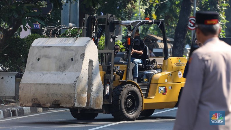Petugas memindahkan barier beton menggunakan alat berat untuk penutupan ruas jalan di kawasan Jalan Medan Merdeka Barat, Jakarta, Kamis (6/6/2024). (CNBC Indonesia/Faisal Rahman)