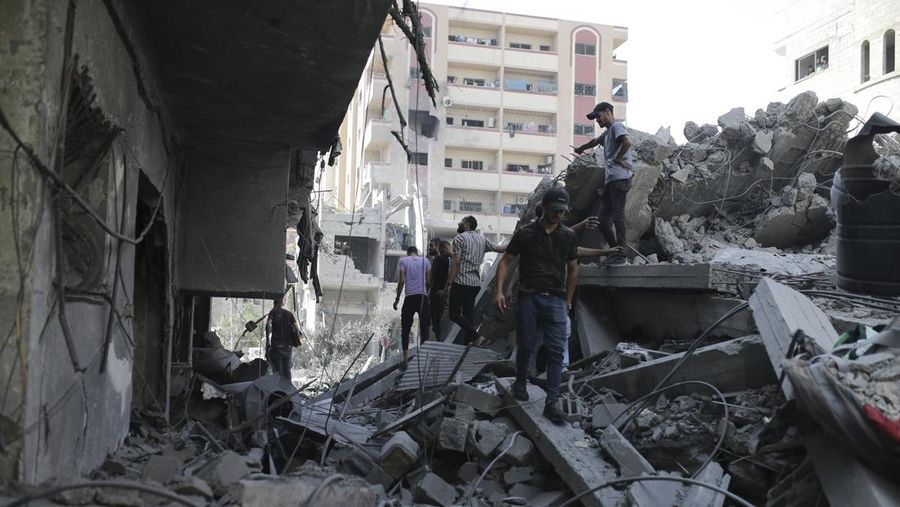 Orang-orang berjalan di antara puing-puing, setelah serangan Israel di daerah tersebut, di mana sandera Israel diselamatkan pada hari Sabtu, ketika jumlah korban tewas warga Palestina meningkat menjadi 274, di tengah konflik Israel-Hamas, di kamp pengungsi Nuseirat di Jalur Gaza tengah, 9 Juni 2024 . (REUTERS/Abed Khaled)