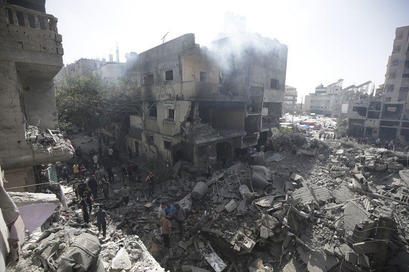 Orang-orang berjalan di antara puing-puing, setelah serangan Israel di daerah tersebut, di mana sandera Israel diselamatkan pada hari Sabtu, ketika jumlah korban tewas warga Palestina meningkat menjadi 274, di tengah konflik Israel-Hamas, di kamp pengungsi Nuseirat di Jalur Gaza tengah, 9 Juni 2024 . (REUTERS/Abed Khaled)