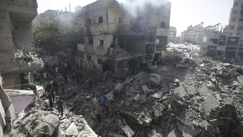 Orang-orang berjalan di antara puing-puing, setelah serangan Israel di daerah tersebut, di mana sandera Israel diselamatkan pada hari Sabtu, ketika jumlah korban tewas warga Palestina meningkat menjadi 274, di tengah konflik Israel-Hamas, di kamp pengungsi Nuseirat di Jalur Gaza tengah, 9 Juni 2024 . (REUTERS/Abed Khaled)