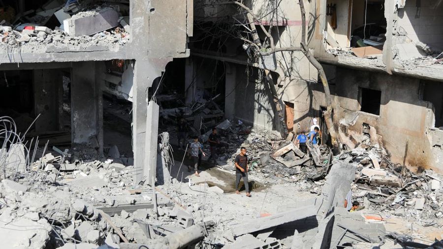 Orang-orang berjalan di antara puing-puing, setelah serangan Israel di daerah tersebut, di mana sandera Israel diselamatkan pada hari Sabtu, ketika jumlah korban tewas warga Palestina meningkat menjadi 274, di tengah konflik Israel-Hamas, di kamp pengungsi Nuseirat di Jalur Gaza tengah, 9 Juni 2024 . (REUTERS/Abed Khaled)