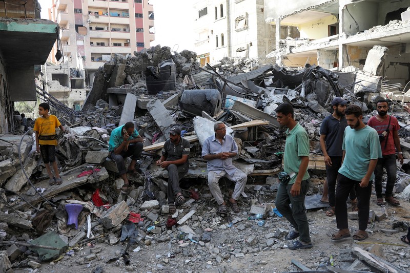 Orang-orang berjalan di antara puing-puing, setelah serangan Israel di daerah tersebut, di mana sandera Israel diselamatkan pada hari Sabtu, ketika jumlah korban tewas warga Palestina meningkat menjadi 274, di tengah konflik Israel-Hamas, di kamp pengungsi Nuseirat di Jalur Gaza tengah, 9 Juni 2024 . (REUTERS/Abed Khaled)