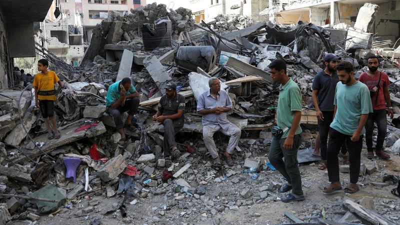 Orang-orang berjalan di antara puing-puing, setelah serangan Israel di daerah tersebut, di mana sandera Israel diselamatkan pada hari Sabtu, ketika jumlah korban tewas warga Palestina meningkat menjadi 274, di tengah konflik Israel-Hamas, di kamp pengungsi Nuseirat di Jalur Gaza tengah, 9 Juni 2024 . (REUTERS/Abed Khaled)