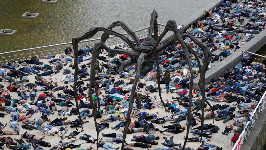 Para pengunjuk rasa berbaring di luar Museum seni modern Guggenheim Bilbao untuk meniru korban jiwa di Gaza, selama protes yang diselenggarakan oleh kolektif Gernika-Palestina dari wilayah Basque Spanyol, di tengah konflik Israel-Hamas, di Bilbao, Spanyol, 8 Juni. 2024. (REUTERS/Vincent West)