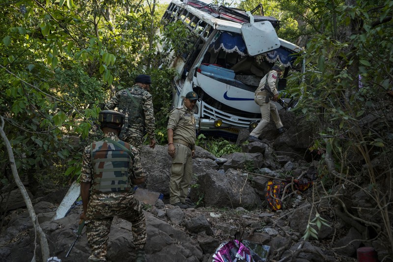 Petugas keamanan memeriksa sebuah bus yang jatuh ke jurang yang dalam pada hari Minggu setelah ditembaki oleh tersangka militan di distrik Reasi, Jammu dan Kashmir, Senin, 10 Juni 2024. Bus itu membawa peziarah ke base camp kuil Hindu yang terkenal itu Mata Vaishno Devi saat diserang menewaskan sedikitnya sembilan orang. (AP Photo/Channi Anand)