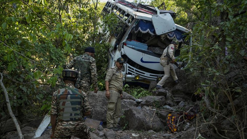Petugas keamanan memeriksa sebuah bus yang jatuh ke jurang yang dalam pada hari Minggu setelah ditembaki oleh tersangka militan di distrik Reasi, Jammu dan Kashmir, Senin, 10 Juni 2024. Bus itu membawa peziarah ke base camp kuil Hindu yang terkenal itu Mata Vaishno Devi saat diserang menewaskan sedikitnya sembilan orang. (AP Photo/Channi Anand)
