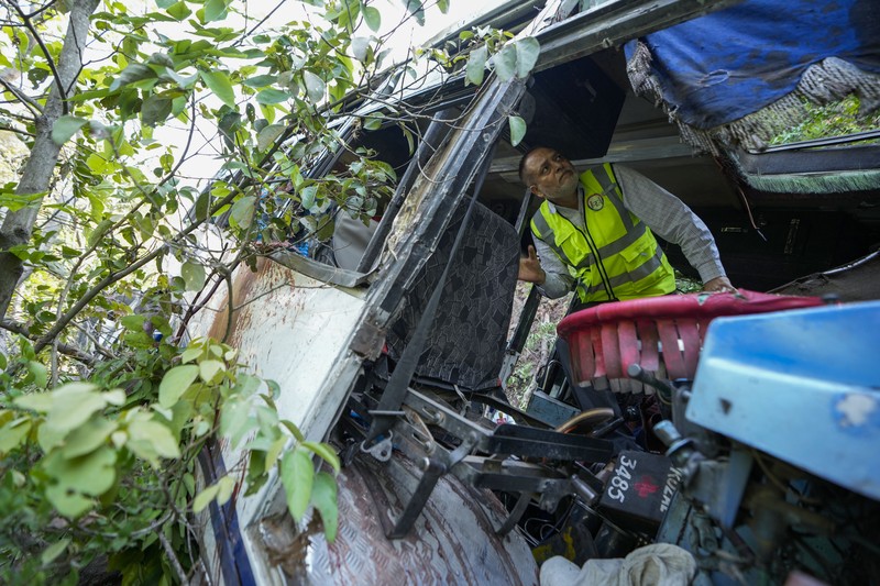 Petugas keamanan memeriksa sebuah bus yang jatuh ke jurang yang dalam pada hari Minggu setelah ditembaki oleh tersangka militan di distrik Reasi, Jammu dan Kashmir, Senin, 10 Juni 2024. Bus itu membawa peziarah ke base camp kuil Hindu yang terkenal itu Mata Vaishno Devi saat diserang menewaskan sedikitnya sembilan orang. (AP Photo/Channi Anand)