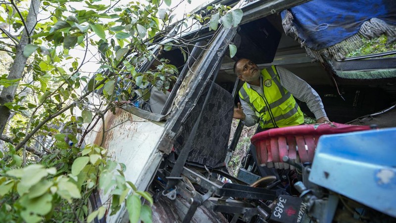 Petugas keamanan memeriksa sebuah bus yang jatuh ke jurang yang dalam pada hari Minggu setelah ditembaki oleh tersangka militan di distrik Reasi, Jammu dan Kashmir, Senin, 10 Juni 2024. Bus itu membawa peziarah ke base camp kuil Hindu yang terkenal itu Mata Vaishno Devi saat diserang menewaskan sedikitnya sembilan orang. (AP Photo/Channi Anand)