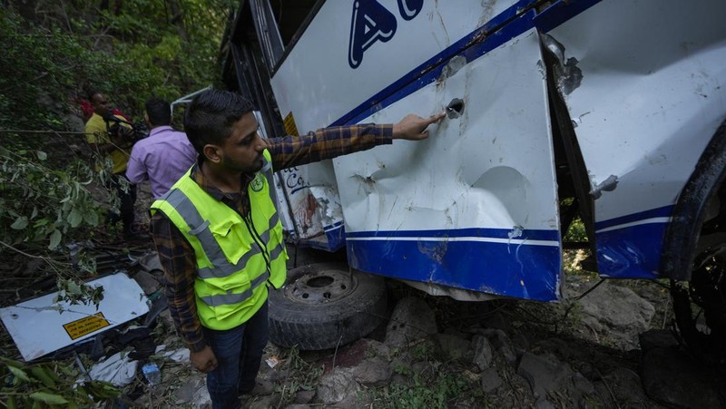 Petugas keamanan memeriksa sebuah bus yang jatuh ke jurang yang dalam pada hari Minggu setelah ditembaki oleh tersangka militan di distrik Reasi, Jammu dan Kashmir, Senin, 10 Juni 2024. Bus itu membawa peziarah ke base camp kuil Hindu yang terkenal itu Mata Vaishno Devi saat diserang menewaskan sedikitnya sembilan orang. (AP Photo/Channi Anand)