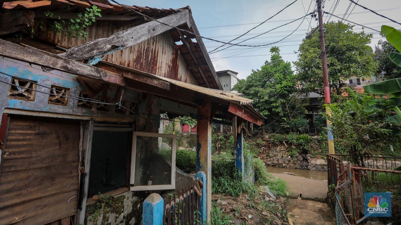 Seorang warga berjalan di dekat rumah yang rusak akibat sering terendam banjir di kawasan Cililitan, Jakarta, Selasa (11/6/2024). Seorang warga berjalan di dekat rumah yang rusak akibat sering terendam banjir di kawasan Cililitan, Jakarta, Selasa (11/6/2024). (CNBC Indonesia/Faisal Rahman)