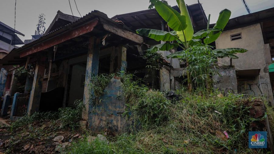 Seorang warga berjalan di dekat rumah yang rusak akibat sering terendam banjir di kawasan Cililitan, Jakarta, Selasa (11/6/2024). (CNBC Indonesia/Faisal Rahman)