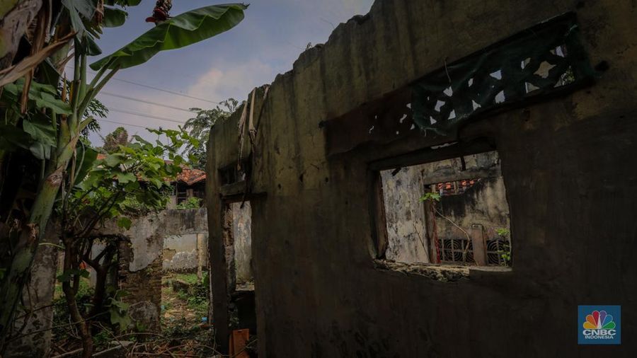 Seorang warga berjalan di dekat rumah yang rusak akibat sering terendam banjir di kawasan Cililitan, Jakarta, Selasa (11/6/2024). (CNBC Indonesia/Faisal Rahman)
