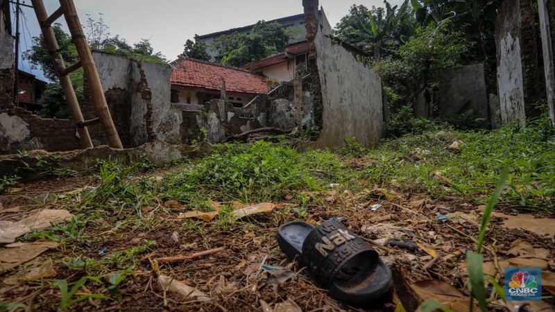 Seorang warga berjalan di dekat rumah yang rusak akibat sering terendam banjir di kawasan Cililitan, Jakarta, Selasa (11/6/2024). Seorang warga berjalan di dekat rumah yang rusak akibat sering terendam banjir di kawasan Cililitan, Jakarta, Selasa (11/6/2024). (CNBC Indonesia/Faisal Rahman)