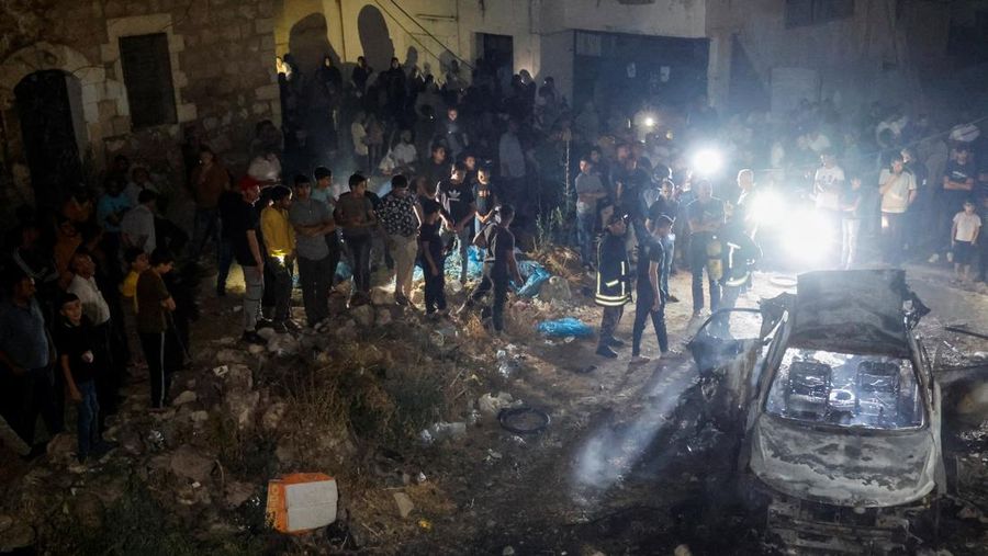 Orang-orang berdiri di dekat kendaraan yang hancur, pasca serangan Israel, di Kafr Dan, dekat Jenin, di Tepi Barat yang diduduki Israel 11 Juni 2024. (REUTERS/Raneen Sawafta)