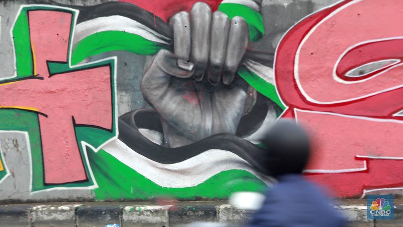 Pengendara melintas didepan mural wajah Perdana Menteri Israel Benjamin Netanyahu di Jakarta, Rabu (12/6/2024). Komunitas Berkemas membuat mural tersebut sebagai bentuk solidaritas dan dukungan kepada warga Palestina atas serangan pasukan Israel ke kota Rafah. (CNBC Indonesia/Muhammad Sabki)