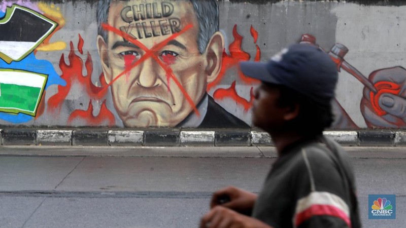 Pengendara melintas didepan mural wajah Perdana Menteri Israel Benjamin Netanyahu di Jakarta, Rabu (12/6/2024). Komunitas Berkemas membuat mural tersebut sebagai bentuk solidaritas dan dukungan kepada warga Palestina atas serangan pasukan Israel ke kota Rafah. (CNBC Indonesia/Muhammad Sabki)