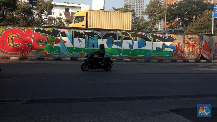 Pengendara melintas didepan mural wajah Perdana Menteri Israel Benjamin Netanyahu di Jakarta, Rabu (12/6/2024). Komunitas Berkemas membuat mural tersebut sebagai bentuk solidaritas dan dukungan kepada warga Palestina atas serangan pasukan Israel ke kota Rafah. (CNBC Indonesia/Muhammad Sabki)