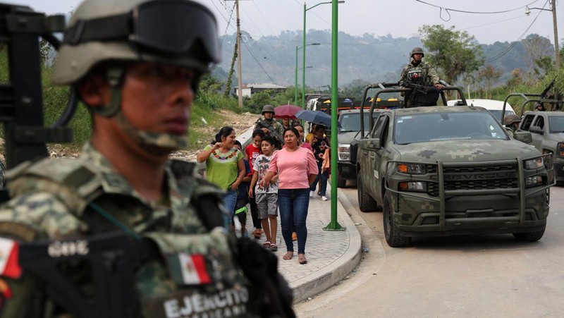 Tentara berjaga-jaga ketika orang-orang yang melarikan diri dari kekerasan geng bersenjata, yang memaksa penduduk untuk mengungsi dengan bantuan otoritas Pemerintah yang mendirikan kamp bagi para pengungsi, tiba di Yajalon, negara bagian Chiapas, Meksiko 9 Juni 2024. (REUTERS/Manuel Orbegozo)