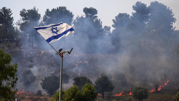 Bendera Israel berkibar setelah serangan udara dari rudal Hizbullah di pinggir jalan dekat perbatasan Israel dengan Lebanon, di Israel. (REUTERS/AYAL MARGOLIN)