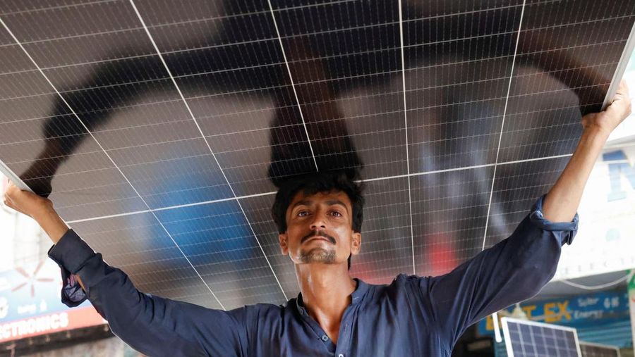 Seorang pekerja memuat panel surya ke kendaraan, di luar toko di pasar yang menjual barang-barang elektronik di Karachi, Pakistan 11 Juni 2024. (REUTERS/Akhtar Soomro)