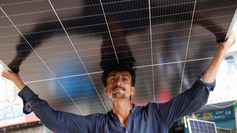 Seorang pekerja memuat panel surya ke kendaraan, di luar toko di pasar yang menjual barang-barang elektronik di Karachi, Pakistan 11 Juni 2024. (REUTERS/Akhtar Soomro)