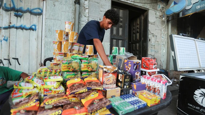 A Palestinian man reaches to products at a stall, ahead of Eid-al-Adha, amid the Israel-Hamas conflict, in Deir Al-Balah, in central Gaza Strip June 15, 2024. REUTERS/Ramadan Abed