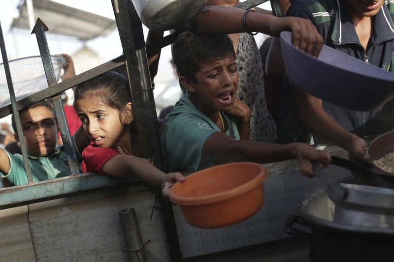 CORRECTS LOCATION TO KHAN YOUNIS - A Palestinian girl reacts as she collects food aid ahead of the upcoming Eid al-Adha holiday in Khan Younis, Gaza Strip, Saturday, June 15, 2024. (AP Photo/Jehad Alshrafi)