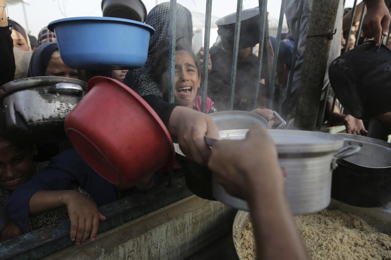 CORRECTS LOCATION TO KHAN YOUNIS - A Palestinian girl reacts as she collects food aid ahead of the upcoming Eid al-Adha holiday in Khan Younis, Gaza Strip, Saturday, June 15, 2024. (AP Photo/Jehad Alshrafi)