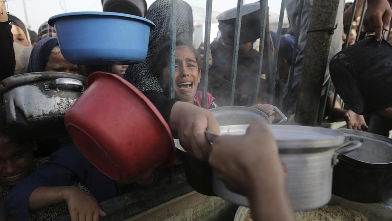 CORRECTS LOCATION TO KHAN YOUNIS - A Palestinian girl reacts as she collects food aid ahead of the upcoming Eid al-Adha holiday in Khan Younis, Gaza Strip, Saturday, June 15, 2024. (AP Photo/Jehad Alshrafi)
