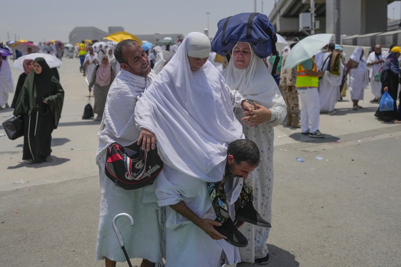 Saudi Arabia Hajj Two muslim pilgrim women share umbrella to protect themself from sun near pillars in the symbolic stoning of the devil, the last rite of the annual hajj, in Mina, near the holy city of Mecca, Saudi Arabia, Sunday, June 16, 2024. Masses of pilgrims on Sunday embarked on a symbolic stoning of the devil in Saudi Arabia. The ritual marks the final days of the Hajj, or Islamic pilgrimage, and the start of the Eid al-Adha celebrations for Muslims around the world. (AP Photo/Rafiq Maqbool)