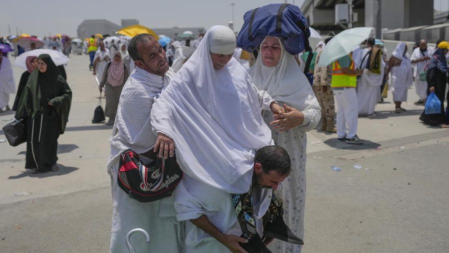 Two muslim pilgrim women share umbrella to protect themself from sun near pillars in the symbolic stoning of the devil, the last rite of the annual hajj, in Mina, near the holy city of Mecca, Saudi Arabia, Sunday, June 16, 2024. Masses of pilgrims on Sunday embarked on a symbolic stoning of the devil in Saudi Arabia. The ritual marks the final days of the Hajj, or Islamic pilgrimage, and the start of the Eid al-Adha celebrations for Muslims around the world. (AP Photo/Rafiq Maqbool)