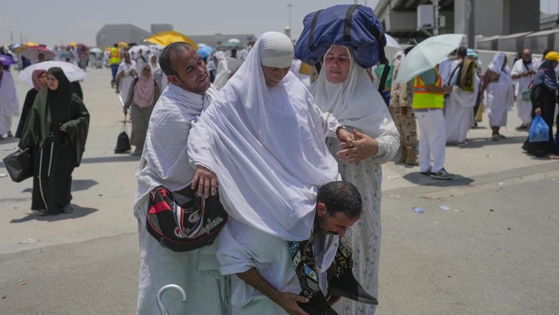 Two muslim pilgrim women share umbrella to protect themself from sun near pillars in the symbolic stoning of the devil, the last rite of the annual hajj, in Mina, near the holy city of Mecca, Saudi Arabia, Sunday, June 16, 2024. Masses of pilgrims on Sunday embarked on a symbolic stoning of the devil in Saudi Arabia. The ritual marks the final days of the Hajj, or Islamic pilgrimage, and the start of the Eid al-Adha celebrations for Muslims around the world. (AP Photo/Rafiq Maqbool)