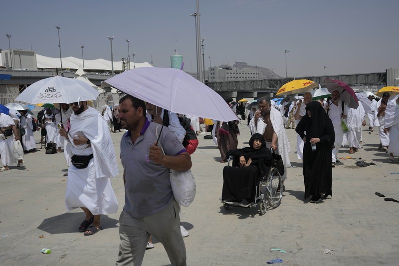 Saudi Arabia Hajj Two muslim pilgrim women share umbrella to protect themself from sun near pillars in the symbolic stoning of the devil, the last rite of the annual hajj, in Mina, near the holy city of Mecca, Saudi Arabia, Sunday, June 16, 2024. Masses of pilgrims on Sunday embarked on a symbolic stoning of the devil in Saudi Arabia. The ritual marks the final days of the Hajj, or Islamic pilgrimage, and the start of the Eid al-Adha celebrations for Muslims around the world. (AP Photo/Rafiq Maqbool)