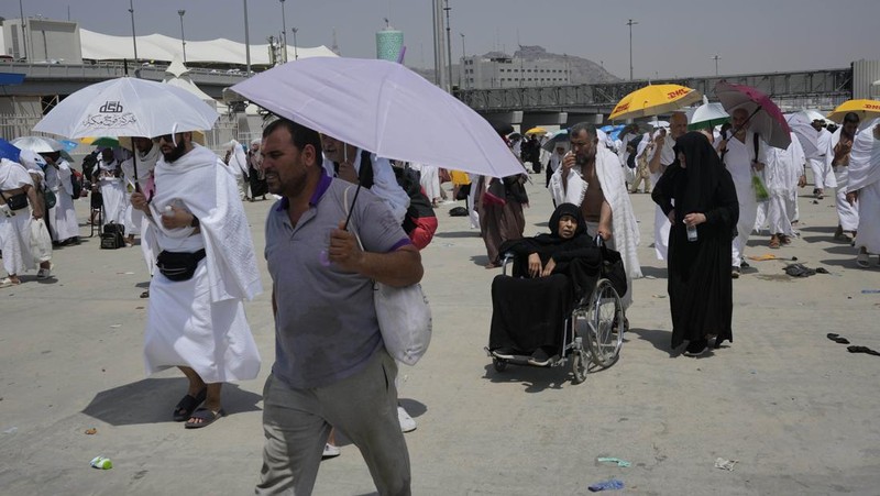 Two muslim pilgrim women share umbrella to protect themself from sun near pillars in the symbolic stoning of the devil, the last rite of the annual hajj, in Mina, near the holy city of Mecca, Saudi Arabia, Sunday, June 16, 2024. Masses of pilgrims on Sunday embarked on a symbolic stoning of the devil in Saudi Arabia. The ritual marks the final days of the Hajj, or Islamic pilgrimage, and the start of the Eid al-Adha celebrations for Muslims around the world. (AP Photo/Rafiq Maqbool)